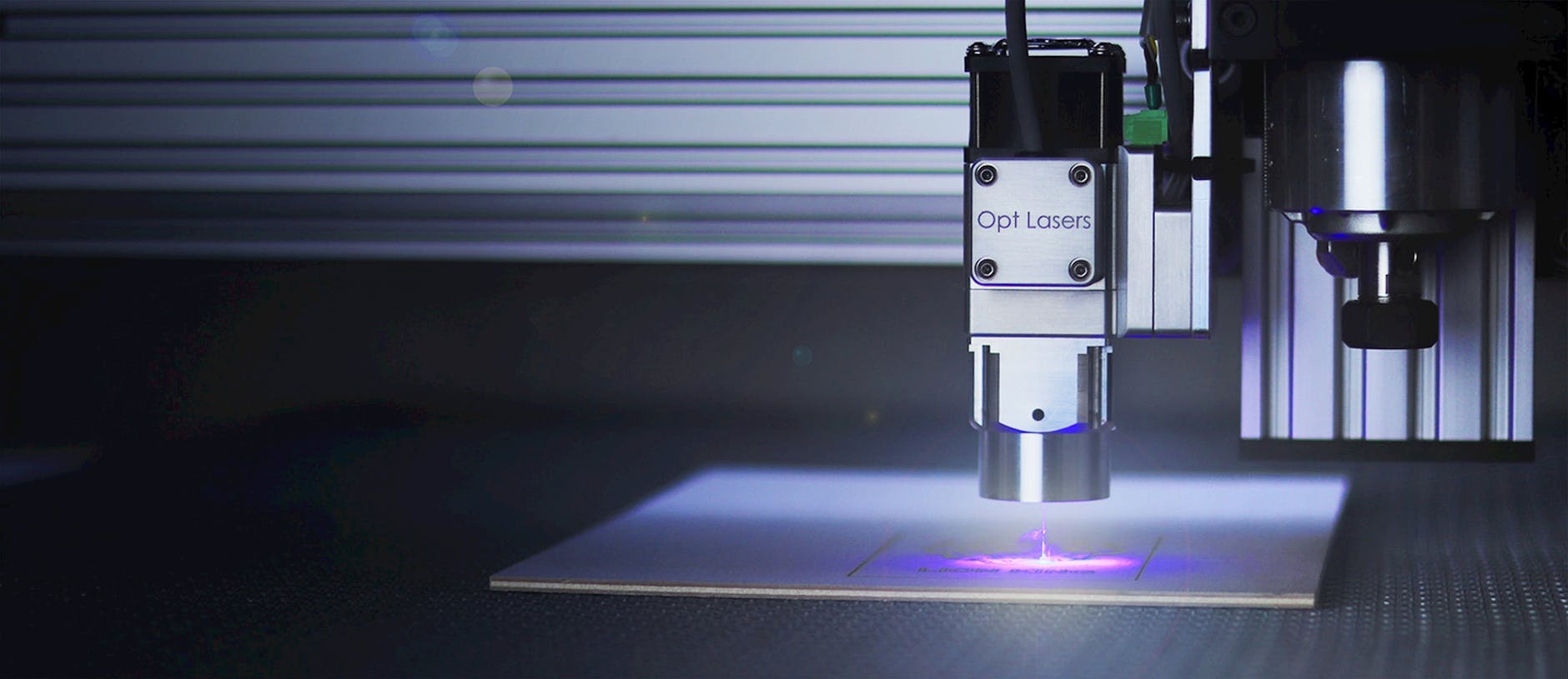 Grawerka laserowa obrabiająca powierzchnię metalu w niebieskim świetle