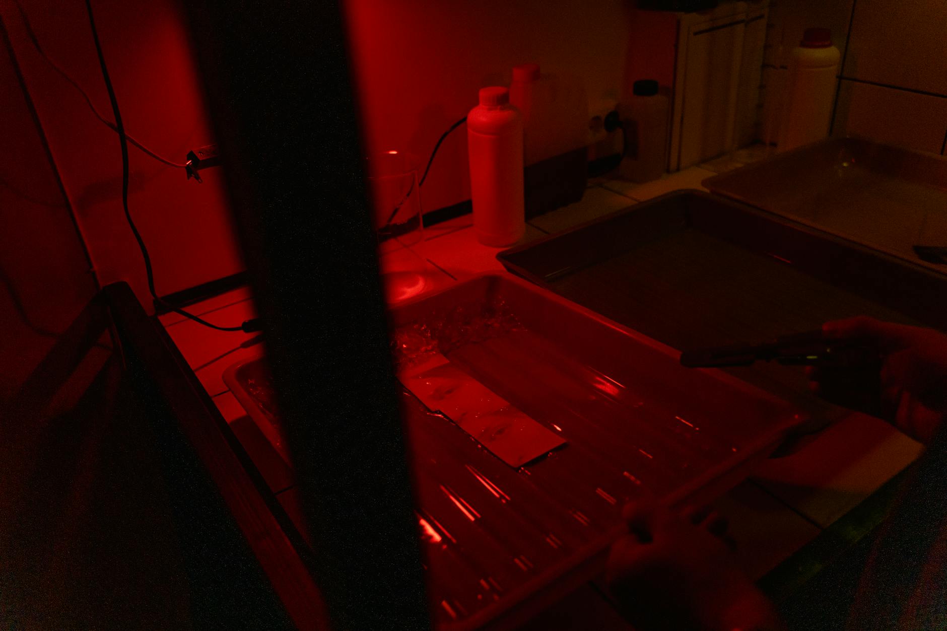 Kuwety do wywoływania zdjęć w ciemni oświetlone czerwonym światłem