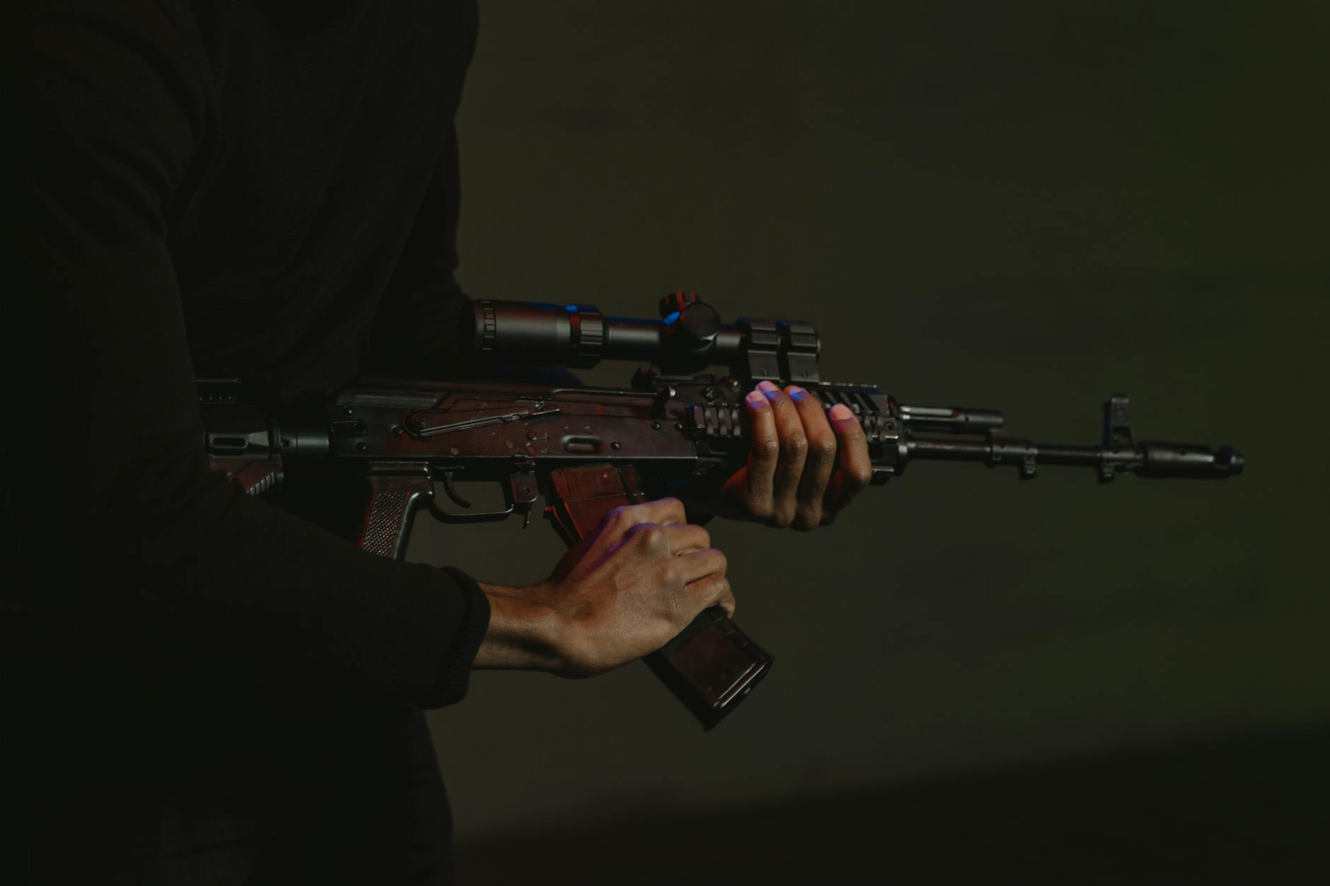 Myśliwy z karabinem z lunetą celuje o zmierzchu