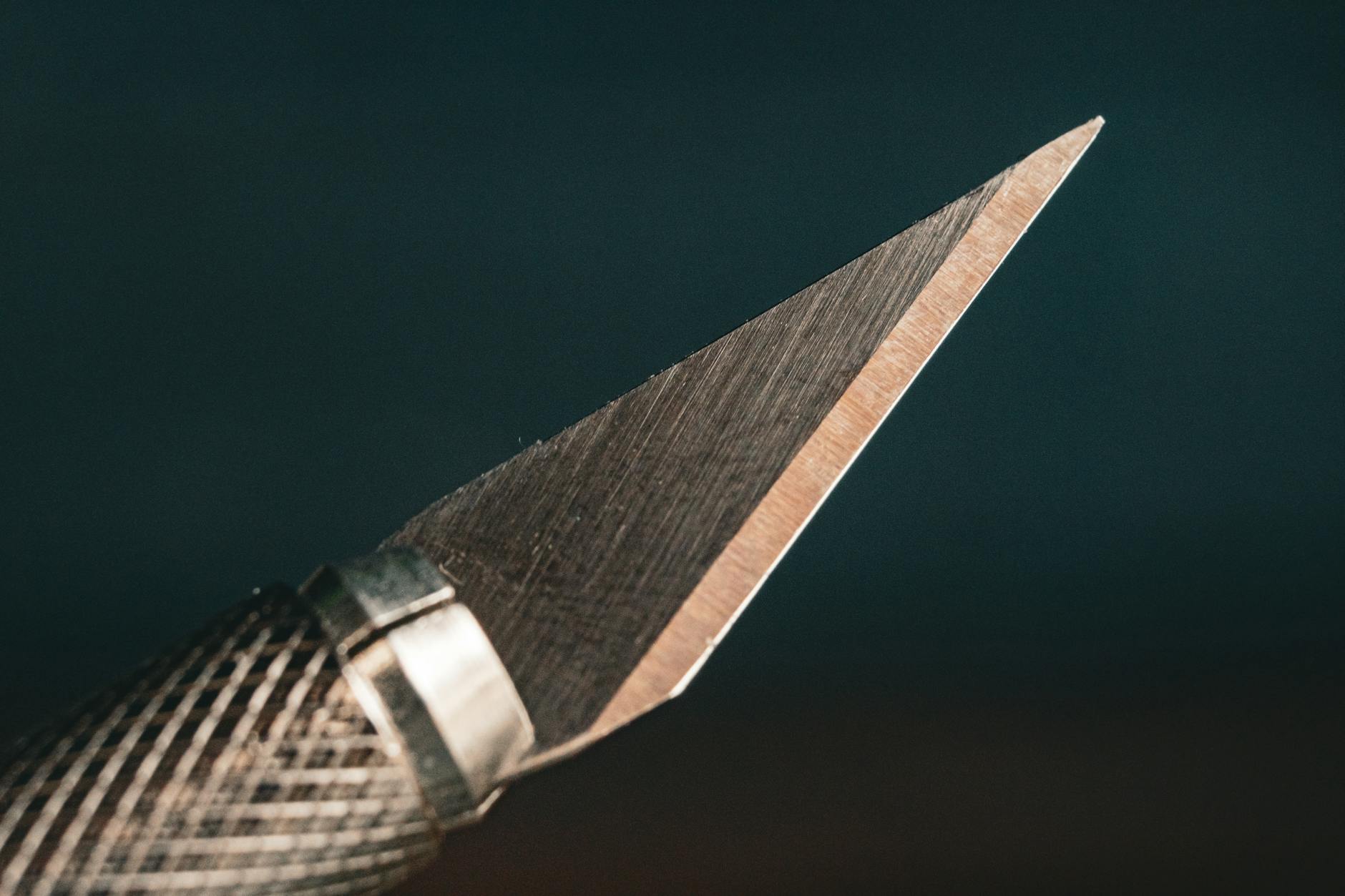 Zbliżenie ostrego noża modelarskiego z fakturowaną rękojeścią