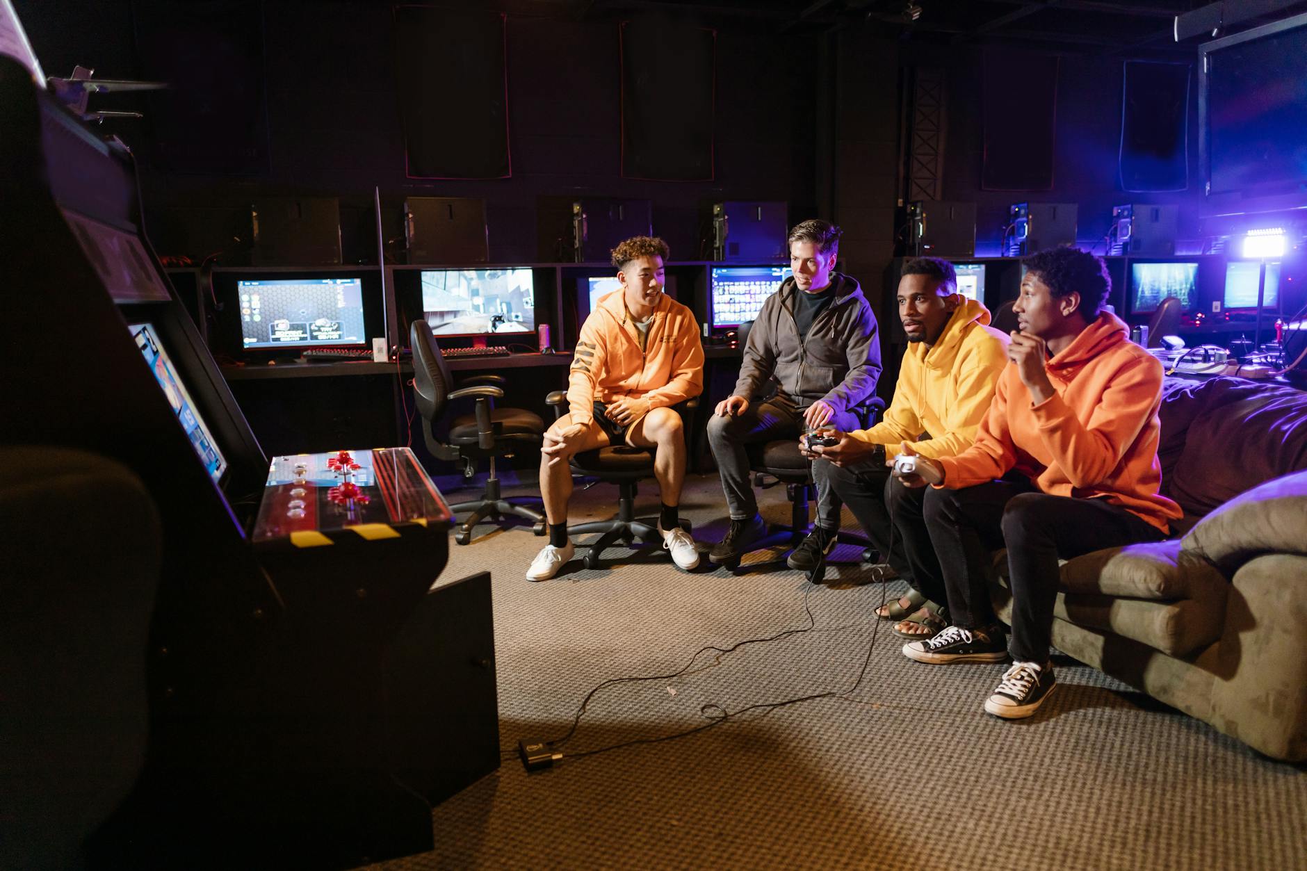 Grupa młodych mężczyzn gra razem na automatach i padach w domu