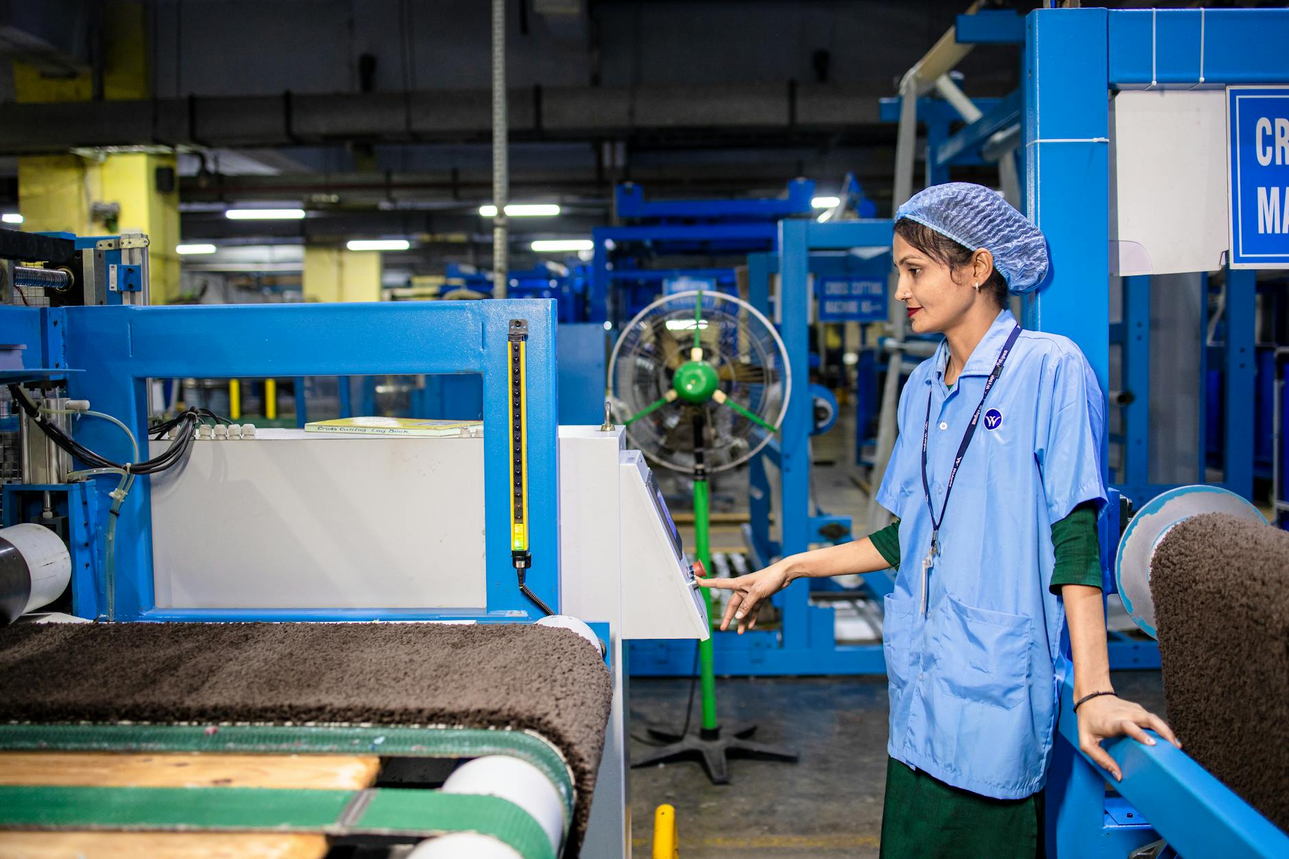 Pracownica przy maszynie tekstylnej w nowoczesnej hali produkcyjnej