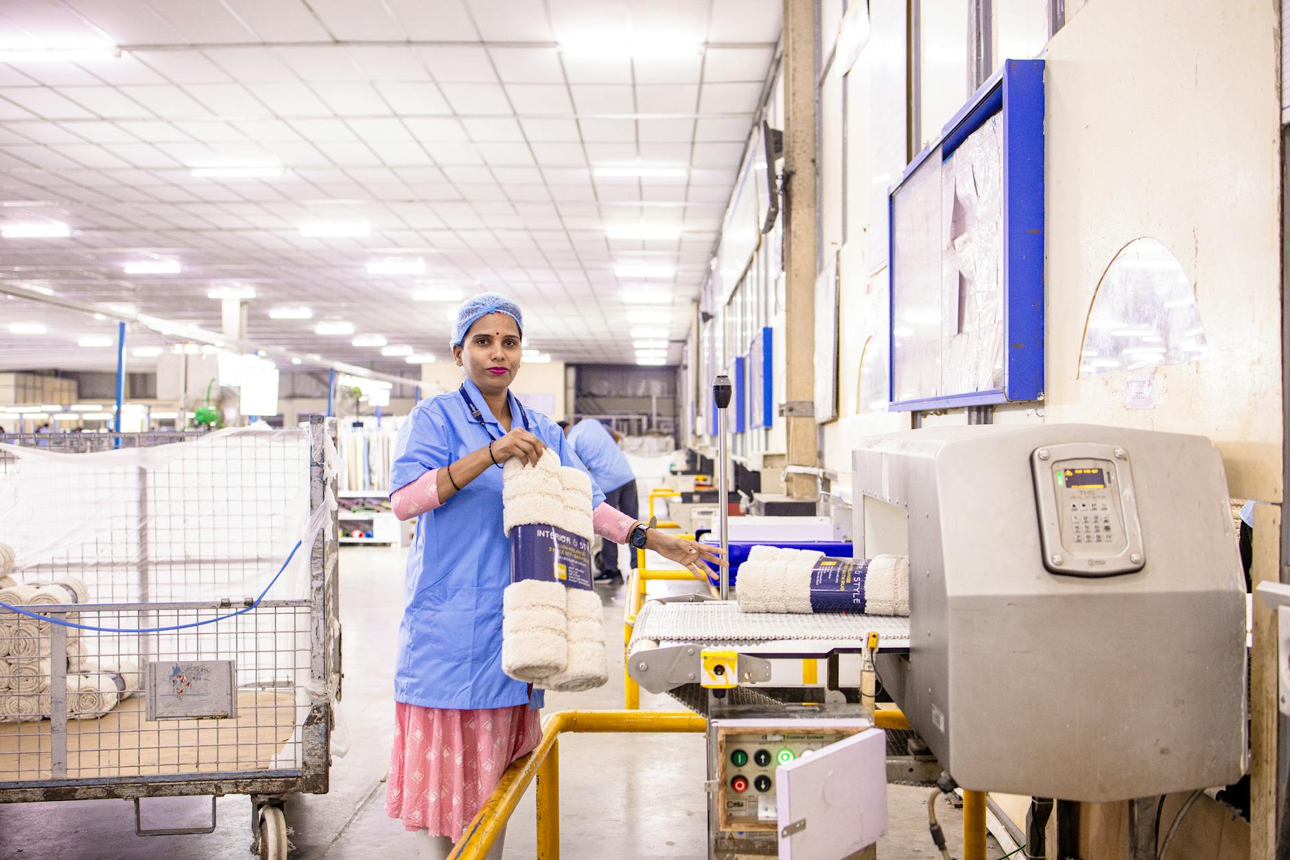 Pracownica zakładu tekstylnego porządkuje produkty w hali produkcyjnej