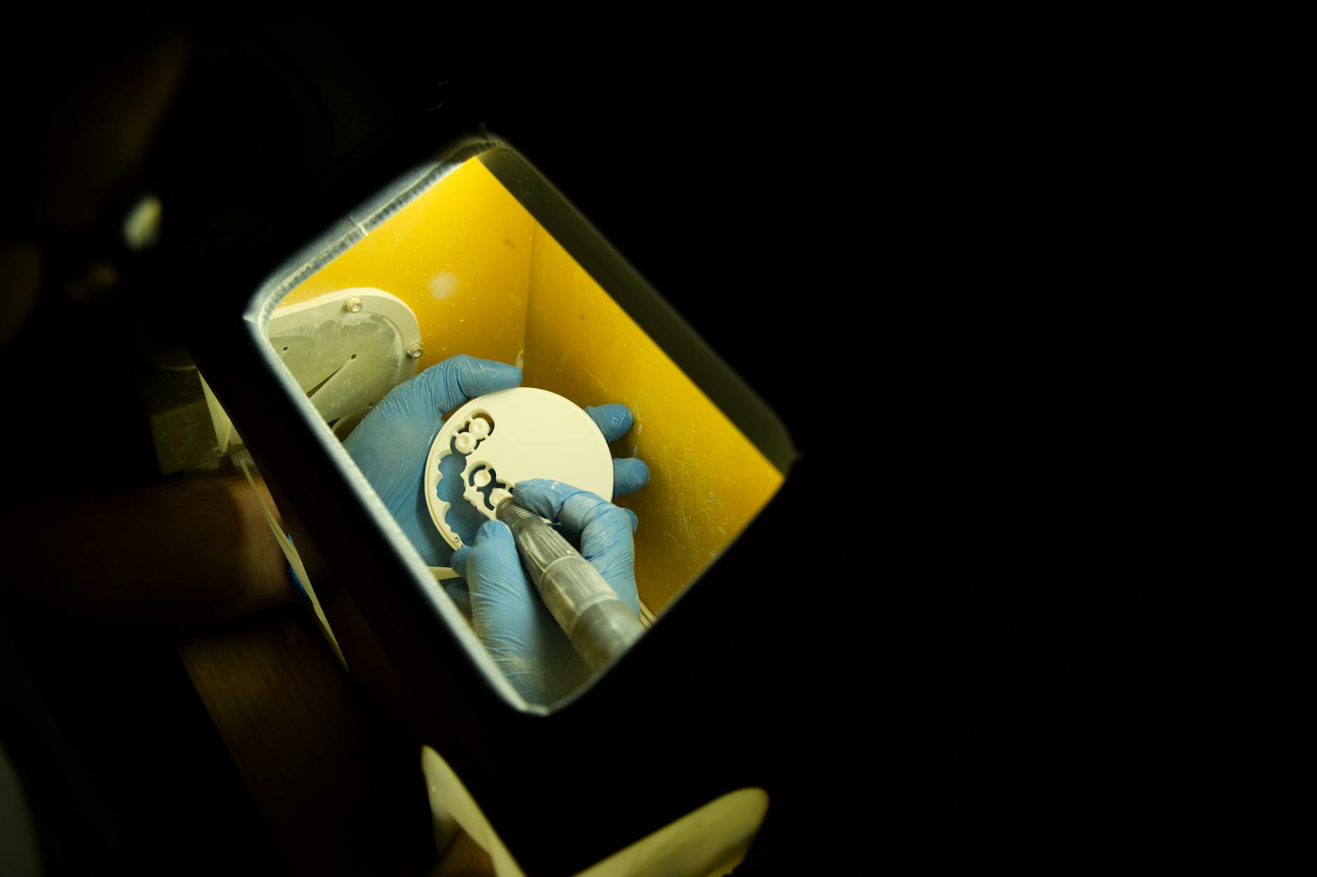 Technik dentystyczny formuje protezę zębową narzędziami na czarnym tle