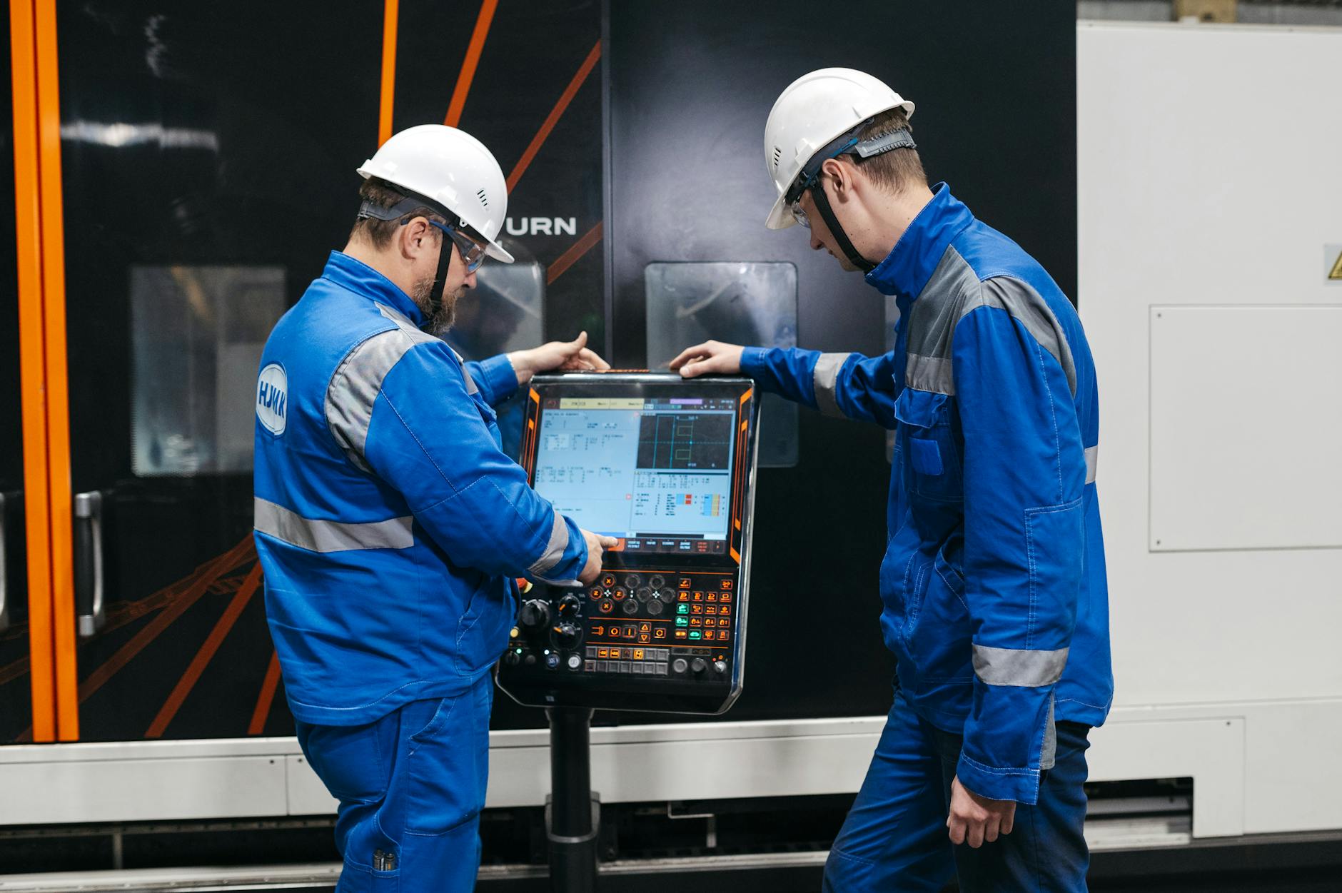 Wersjonowanie modeli i programów NC bez chaosu Dwóch inżynierów obsługuje maszynę CNC w hali produkcyjnej