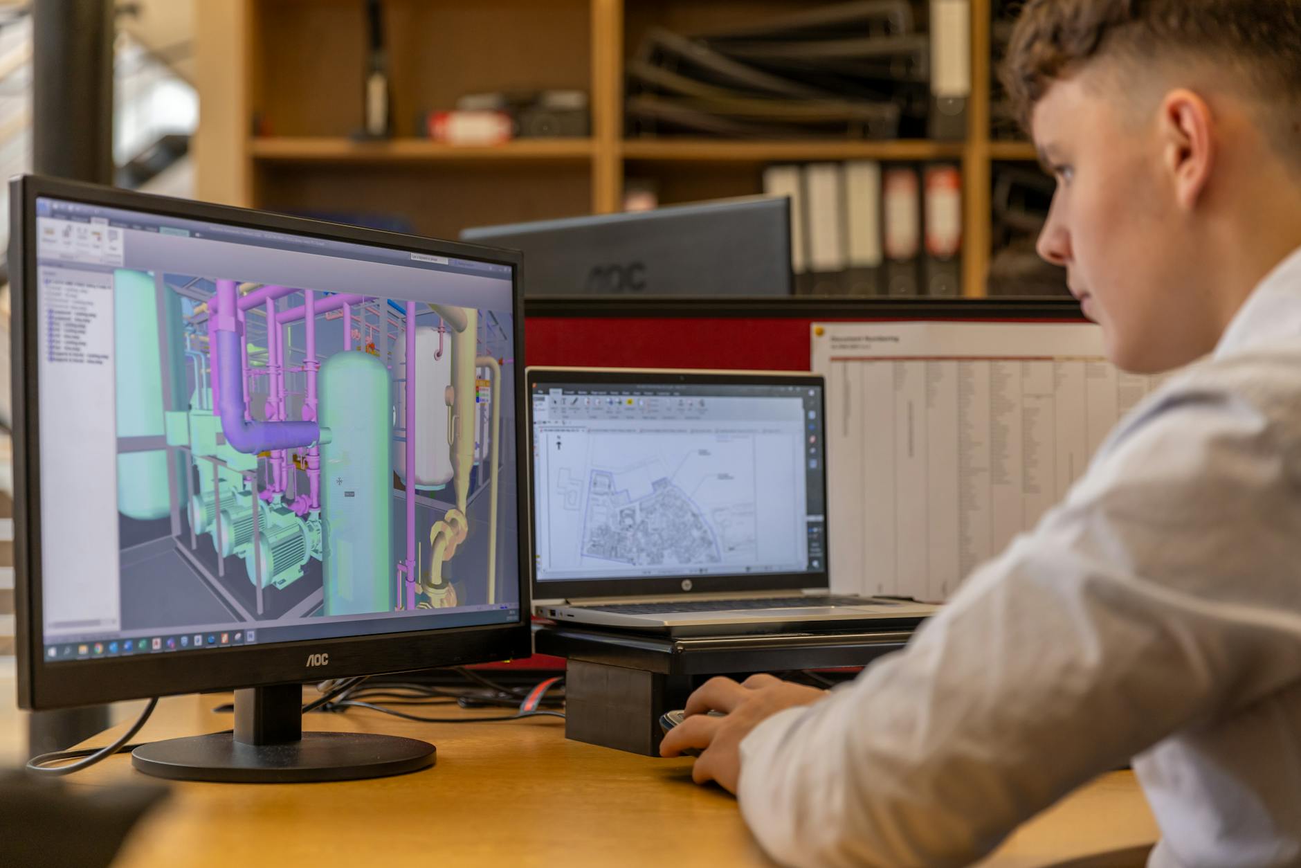 Inżynier przy dwóch monitorach projektuje model CAD w biurze