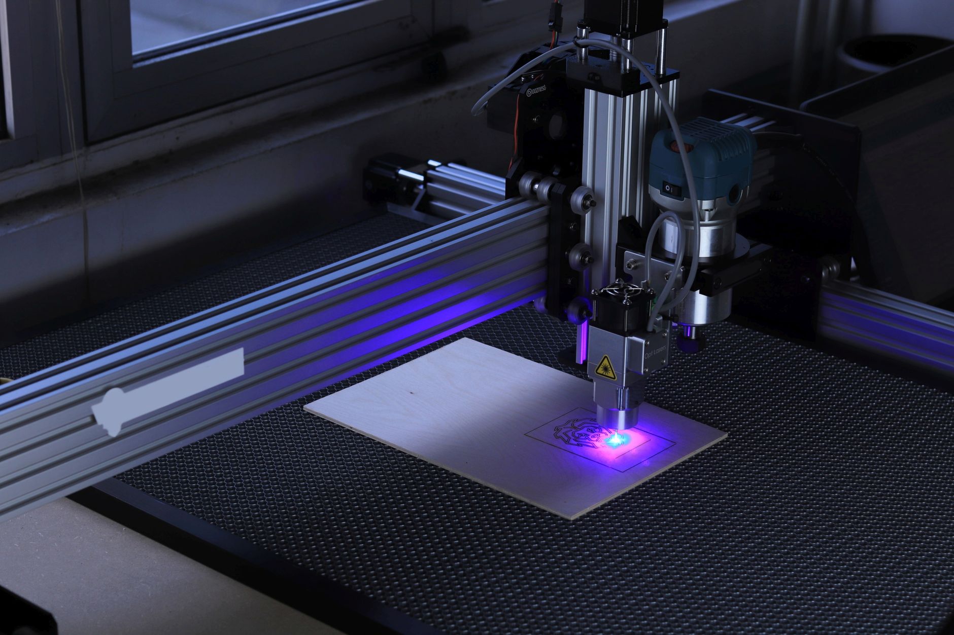 Detal głowicy lasera CNC grawerującej wzór na drewnianej desce